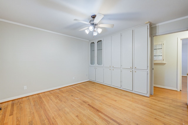 unfurnished bedroom with ornamental molding, light wood-type flooring, baseboards, and a ceiling fan