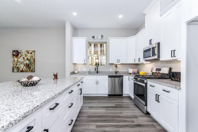 kitchen featuring a sink, white cabinets, appliances with stainless steel finishes, light stone countertops, and recessed lighting