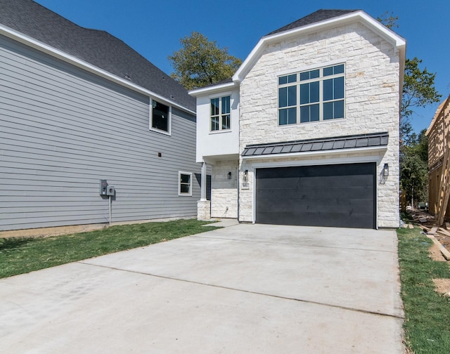 view of front of house featuring stone siding, a standing seam roof, driveway, and a garage