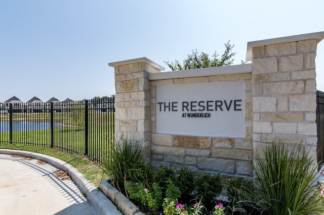 community sign featuring fence and a water view