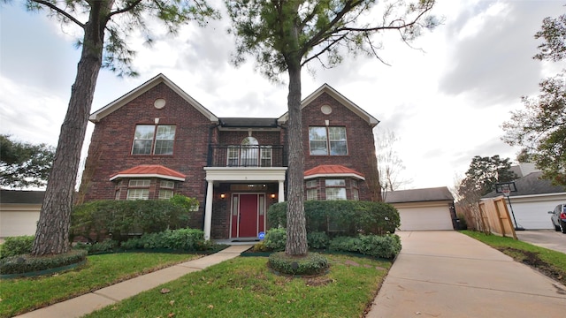 view of front of house featuring an outbuilding, a balcony, a garage, brick siding, and a front yard