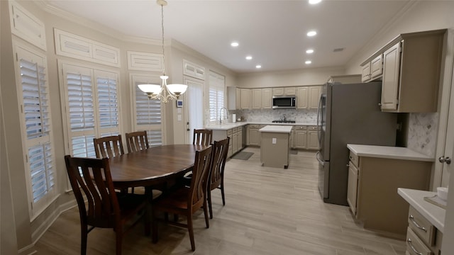 dining area with light wood-style floors, ornamental molding, an inviting chandelier, and recessed lighting