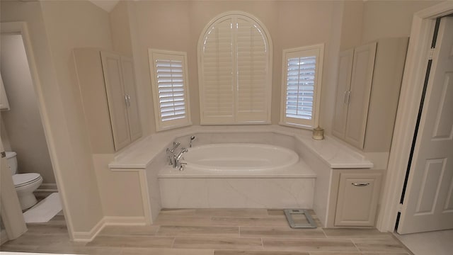 full bathroom with wood tiled floor, a garden tub, and toilet