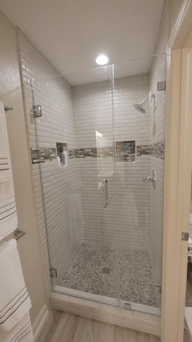 bathroom with a stall shower and wood finished floors