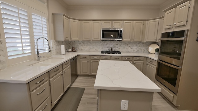 kitchen featuring stainless steel appliances, crown molding, a sink, and a kitchen island