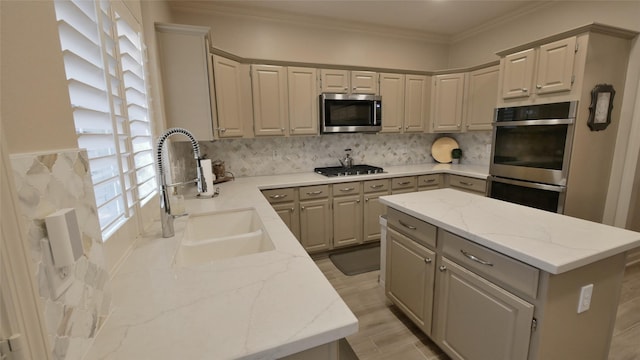 kitchen with light stone countertops, appliances with stainless steel finishes, a sink, and gray cabinetry