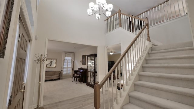 stairway featuring wood finished floors, a towering ceiling, and an inviting chandelier