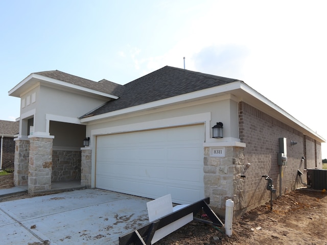 8311 Oceanmist Cove Dr, Cypress, TX 77433 - view of home's exterior featuring roof with shingles, stone siding, cooling unit, concrete driveway, and an attached garage