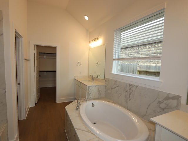 8311 Oceanmist Cove Dr, Cypress, TX 77433 - bathroom featuring vanity, a bath, wood finished floors, lofted ceiling, and a spacious closet