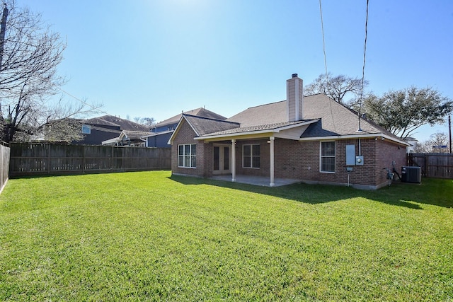 rear view of property with brick siding, a chimney, a patio area, cooling unit, and a fenced backyard