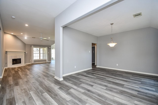 unfurnished living room with lofted ceiling, a tile fireplace, dark wood-type flooring, visible vents, and baseboards