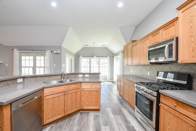 kitchen with pendant lighting, stainless steel appliances, decorative backsplash, vaulted ceiling, and a sink