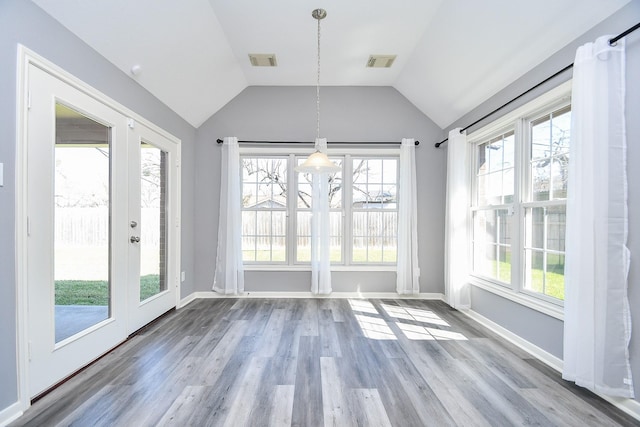 unfurnished dining area featuring lofted ceiling, light wood-style flooring, visible vents, and baseboards