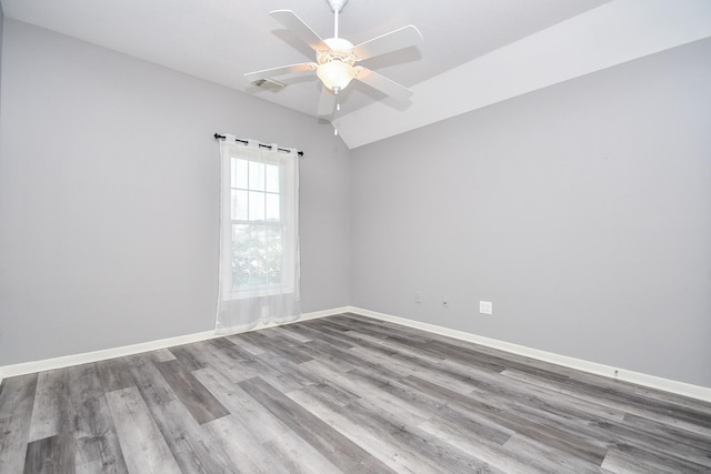 unfurnished room featuring ceiling fan, lofted ceiling, wood finished floors, visible vents, and baseboards