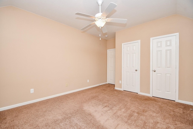 unfurnished bedroom with a ceiling fan, carpet, vaulted ceiling, and baseboards