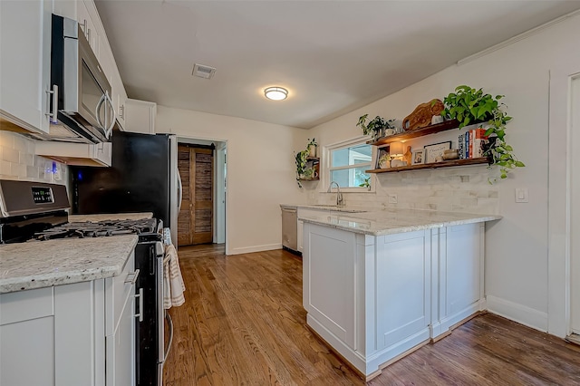 kitchen featuring decorative backsplash, light stone counters, stainless steel appliances, white cabinetry, and open shelves