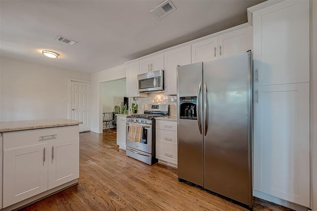 kitchen with tasteful backsplash, visible vents, white cabinets, appliances with stainless steel finishes, and light wood-style floors