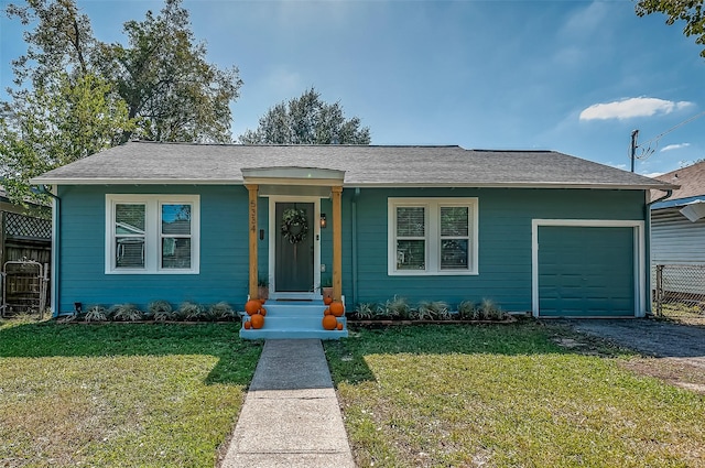 view of front of home featuring an attached garage, driveway, a shingled roof, and a front yard