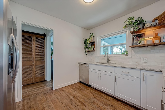 kitchen featuring stainless steel appliances, a sink, white cabinets, light wood-type flooring, and open shelves