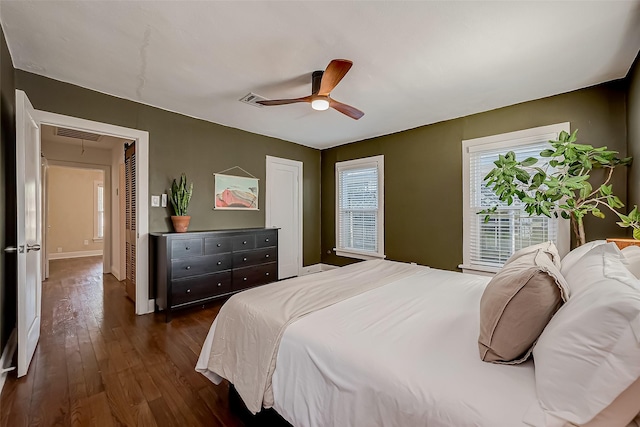 bedroom featuring attic access, dark wood-type flooring, visible vents, and a ceiling fan