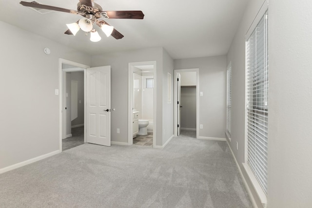 unfurnished bedroom featuring a walk in closet, carpet flooring, connected bathroom, and baseboards