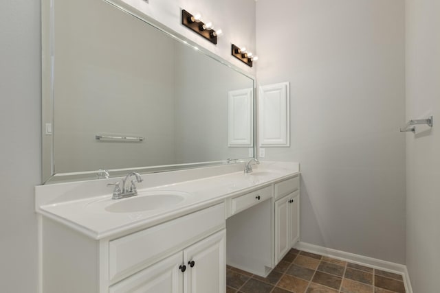 full bath featuring double vanity, a sink, and baseboards