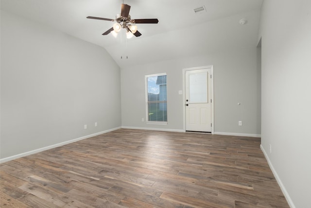 spare room with baseboards, visible vents, ceiling fan, wood finished floors, and vaulted ceiling