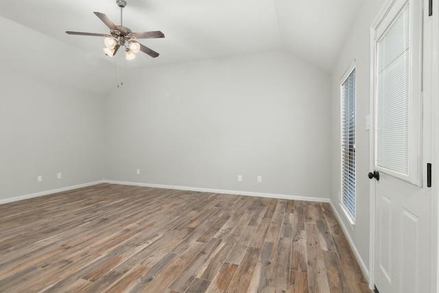 unfurnished bedroom featuring baseboards, lofted ceiling, ceiling fan, wood finished floors, and multiple windows