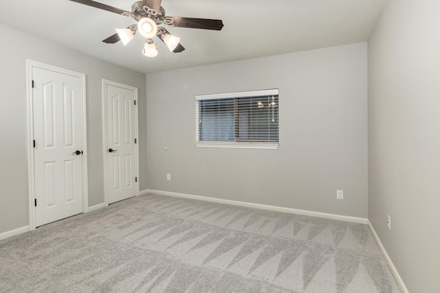 spare room with carpet, a ceiling fan, and baseboards