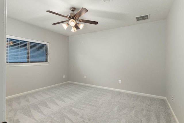 carpeted spare room with a ceiling fan, visible vents, and baseboards