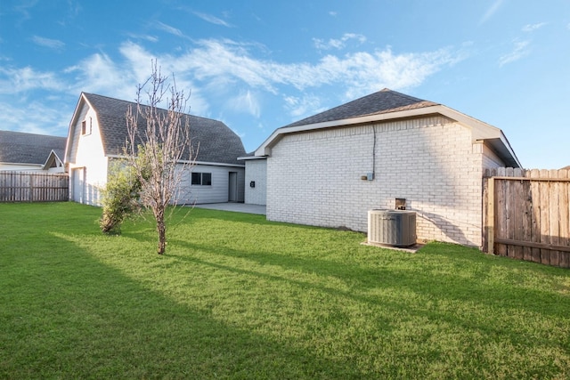 back of property featuring a yard, fence, central AC, and brick siding