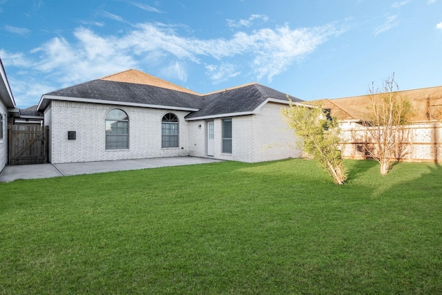 rear view of property with brick siding, a lawn, a patio area, and fence