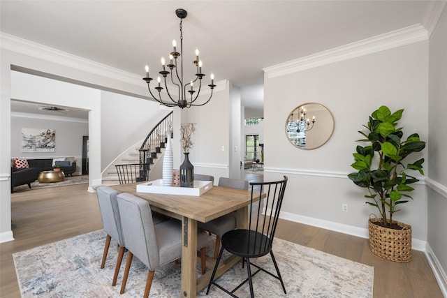 dining area featuring stairs, an inviting chandelier, wood finished floors, and crown molding