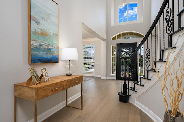 entrance foyer with baseboards, a high ceiling, stairway, and wood finished floors