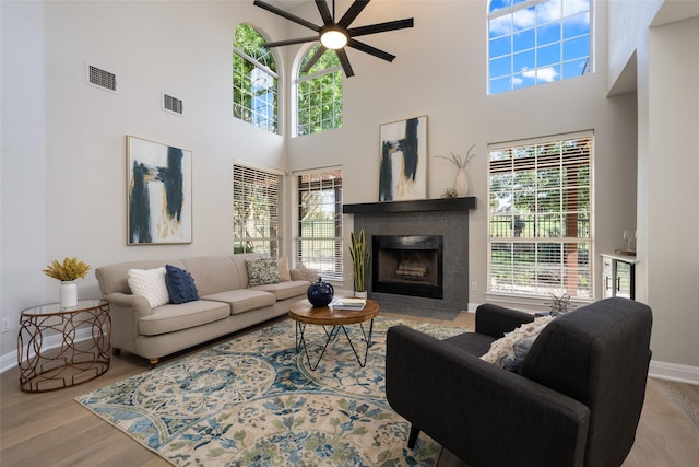 living room featuring light wood-style floors, a fireplace with flush hearth, visible vents, and baseboards