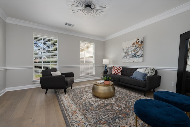 living room featuring baseboards, visible vents, wood finished floors, and ornamental molding