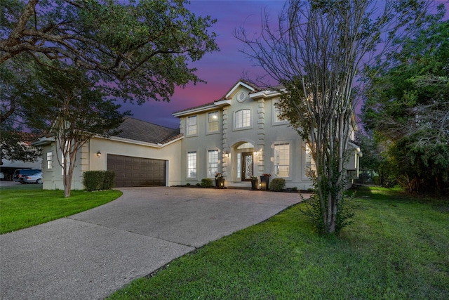 view of front facade with a front yard, driveway, an attached garage, and stucco siding