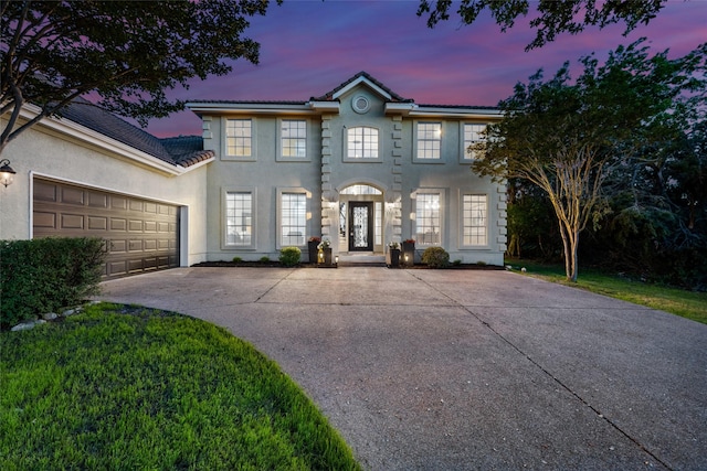 colonial inspired home with a garage, driveway, a tiled roof, and stucco siding