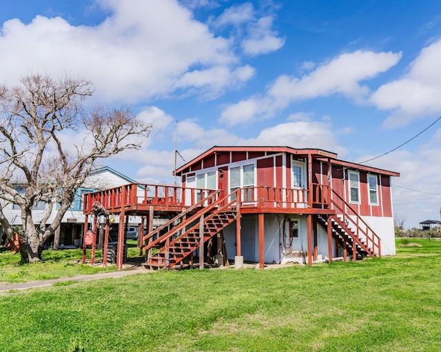 rear view of property featuring a deck, stairway, and a lawn