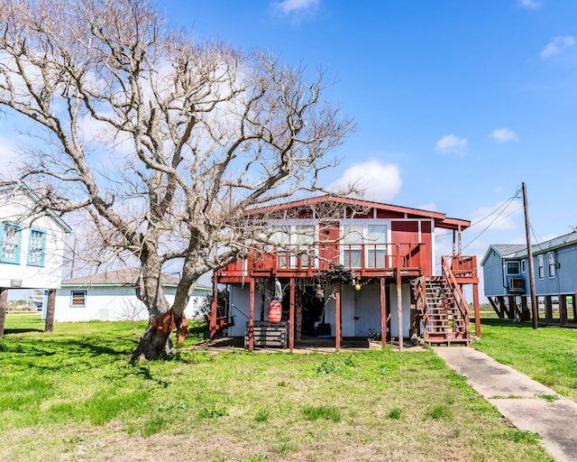 rear view of house featuring stairs, a deck, and a lawn