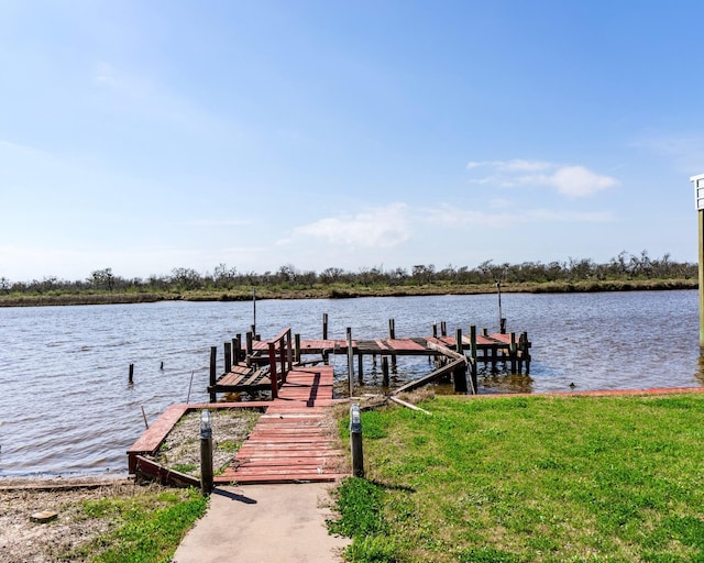 view of dock with a yard and a water view