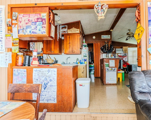 kitchen featuring a sink, wood walls, vaulted ceiling, and a ceiling fan