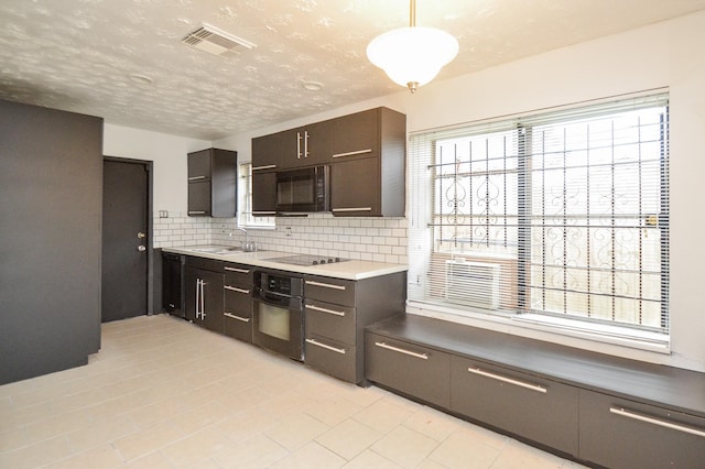 kitchen with visible vents, hanging light fixtures, decorative backsplash, a sink, and black appliances