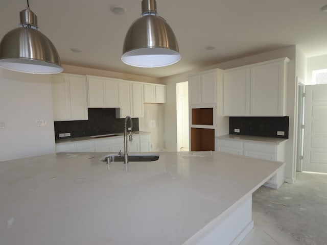 8502 Pier Cove Dr, Cypress, TX 77433 - kitchen with a sink, tasteful backsplash, white cabinetry, hanging light fixtures, and concrete flooring