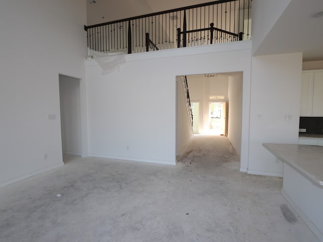 8502 Pier Cove Dr, Cypress, TX 77433 - unfurnished living room featuring a towering ceiling, concrete flooring, and baseboards