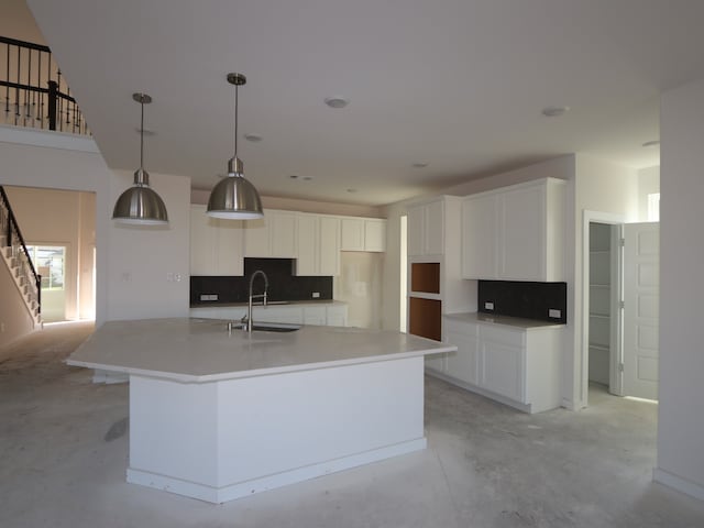 8502 Pier Cove Dr, Cypress, TX 77433 - kitchen with tasteful backsplash, white cabinets, a large island with sink, concrete flooring, and a sink