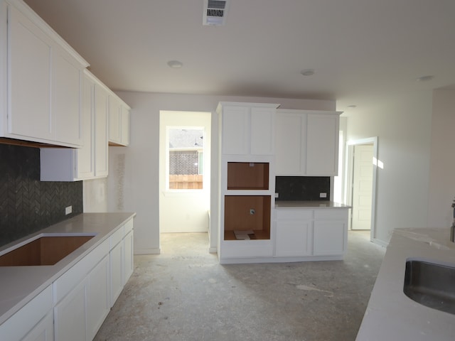 8502 Pier Cove Dr, Cypress, TX 77433 - kitchen featuring concrete floors, decorative backsplash, white cabinetry, and a sink