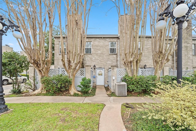 view of front of property with fence, cooling unit, and brick siding