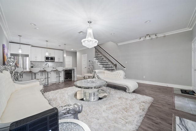 living room featuring beverage cooler, visible vents, ornamental molding, and a notable chandelier