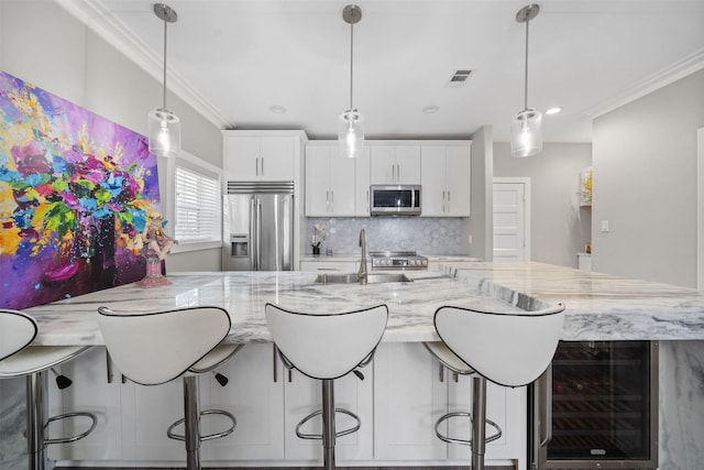 kitchen with stainless steel appliances, wine cooler, decorative light fixtures, and white cabinets